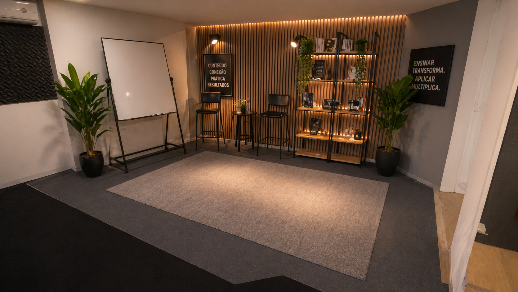 Auditório do Hub vazio com palco, TV cenográfica, painéis acústicos e iluminação warm